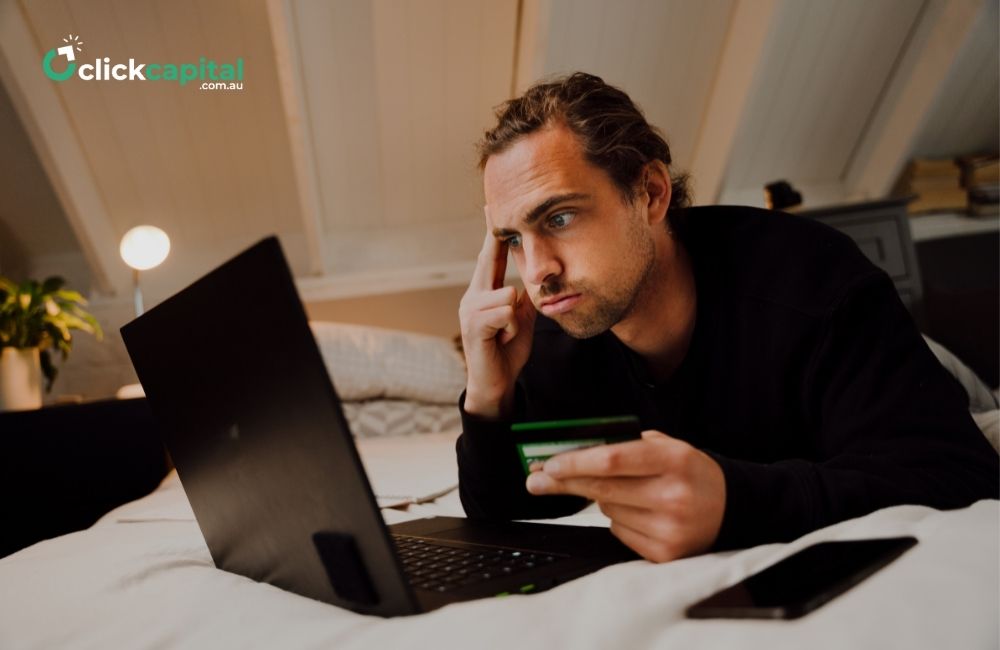 Stressed business owner holding a credit card while paying in his laptop