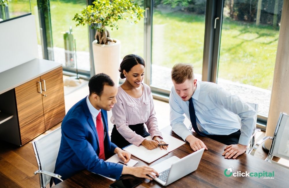 three business owners looking at laptop searching for types of collateral for their loan