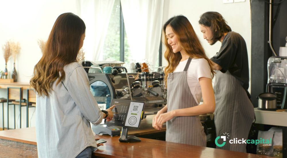 customer paying with a customer facing display / screen in the cafe counter with an asian waitress and barista